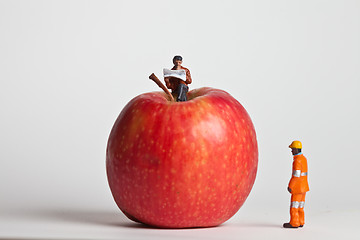 Image showing Miniature people in action sitting on an apple