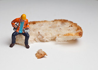 Image showing Miniature people in action with a piece of bread