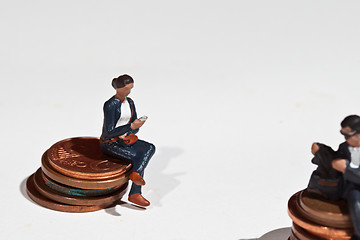 Image showing Miniature people sitting on coins