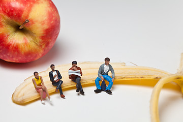 Image showing Miniature people in action sitting on a banan