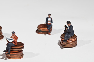 Image showing Miniature people sitting on coins