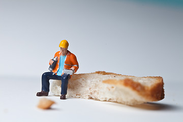 Image showing Miniature people in action with a piece of bread