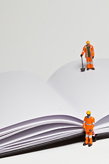 Image showing Miniature people in action worker on an open book