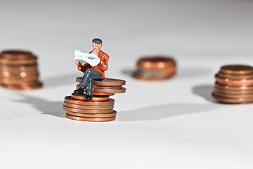 Image showing Miniature people sitting on coins