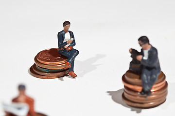 Image showing Miniature people sitting on coins