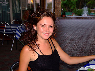 Image showing The young beautiful smiling girl sits at restaurant