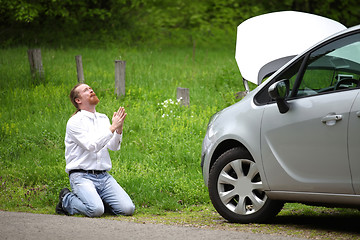 Image showing Funny driver praying a broken car by the road  