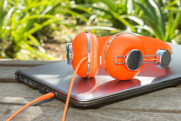 Image showing Bright coloured orange headphones and mobile computer