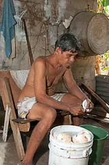 Image showing native senior man cleaning slicing fresh coconut for production 