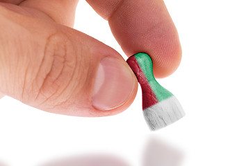 Image showing Hand holding wooden pawn, flag painting, selective focus