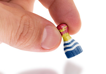 Image showing Hand holding wooden pawn, flag painting, selective focus