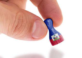 Image showing Hand holding wooden pawn, flag painting, selective focus