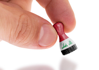 Image showing Hand holding wooden pawn, flag painting, selective focus