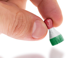 Image showing Hand holding wooden pawn, flag painting, selective focus