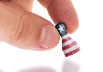 Image showing Hand holding wooden pawn, flag painting, selective focus