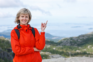 Image showing Happy woman outdoors pointing up at copy space