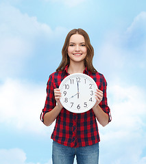 Image showing young woman in casual clothes with wall clock