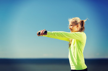 Image showing sporty woman with light dumbbells outdoors