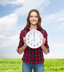 Image showing young woman in casual clothes with wall clock