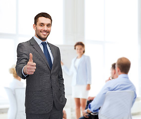 Image showing handsome buisnessman showing thumbs up in office