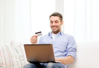 Image showing smiling man working with laptop and credit card