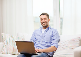 Image showing smiling man working with laptop at home