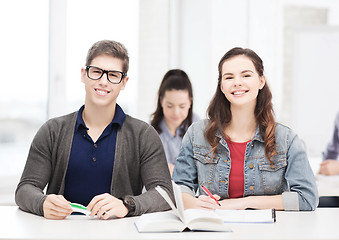 Image showing two teenagers with notebooks and book at school