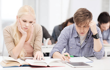 Image showing tired students with tablet pc, notebooks and books