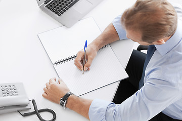 Image showing businessman writing in notebook