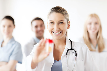 Image showing female doctor with jar of capsules