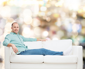 Image showing smiling man lying on sofa