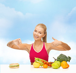 Image showing woman with fruits and hamburger comparing food