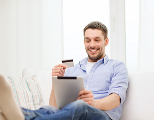 Image showing smiling man working with tablet pc at home