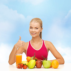 Image showing smiling woman with organic food or fruits on table