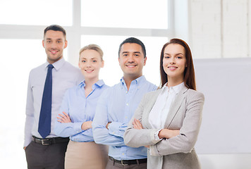 Image showing smiling businesswoman in office with team on back