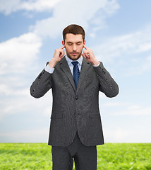 Image showing annoyed businessman covering ears with his hands