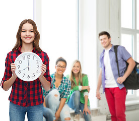 Image showing young woman in casual clothes with wall clock