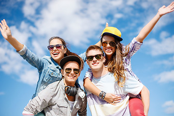 Image showing smiling teenagers in sunglasses having fun outside