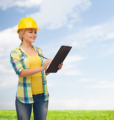 Image showing smiling woman in helmet with clipboard