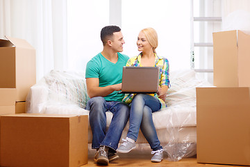 Image showing couple relaxing on sofa with laptop in new home