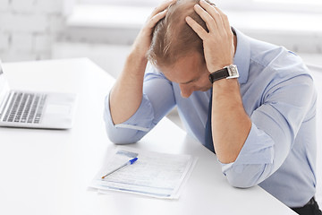 Image showing stressed businessman with papers at work