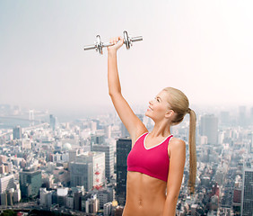 Image showing smiling woman with heavy steel dumbbell