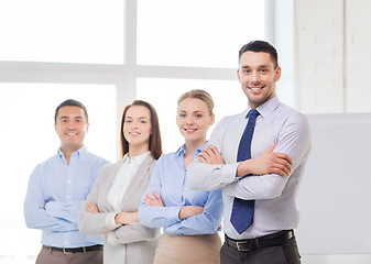 Image showing smiling businessman in office with team on back