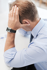 Image showing stressed businessman with papers at work