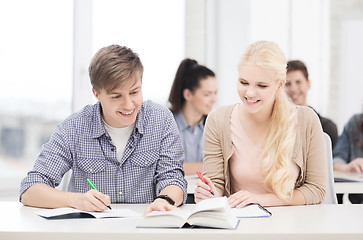 Image showing two teenagers with notebooks and book at school