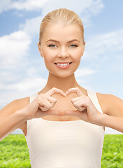 Image showing smiling woman showing heart shape gesture