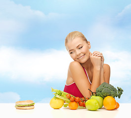 Image showing doubting woman with fruits and hamburger