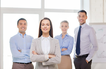 Image showing smiling businesswoman in office with team on back