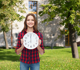 Image showing young woman in casual clothes with wall clock