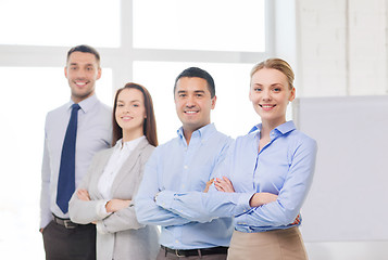 Image showing smiling businesswoman in office with team on back